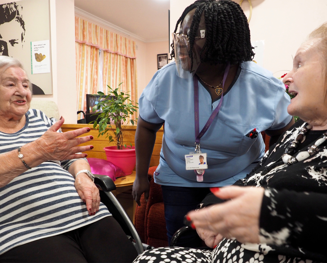 Engage Service image showing a member of staff talking to elderly women in a care setting.