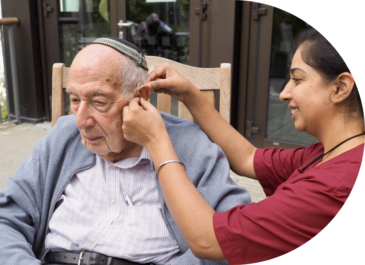Engage | an image showing a member of staff fitting a hearing aid