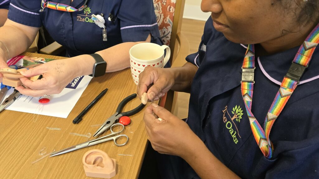 Close up of a team leader changing the tube on a hearing aid.