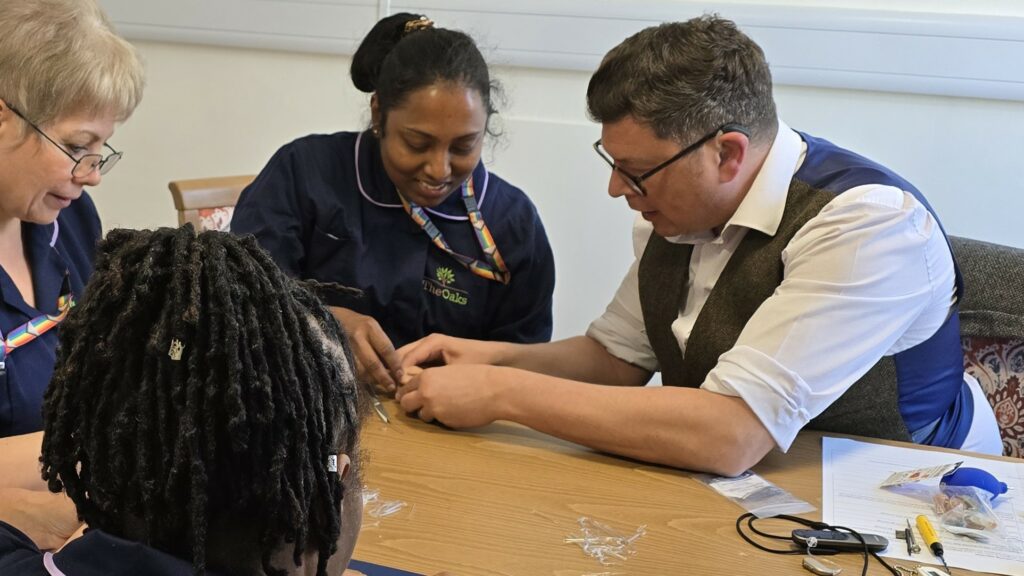 Andrew showing how to change the tube on a hearing aid.